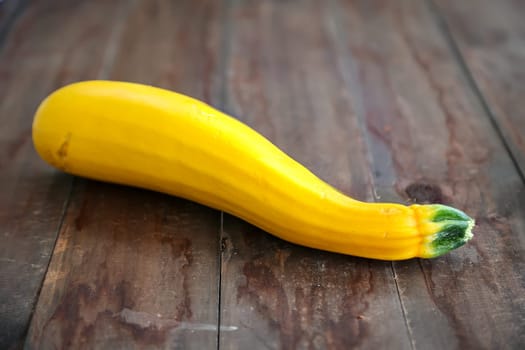 Yellow zucchini on a brown wooden base, ready for preparation.
