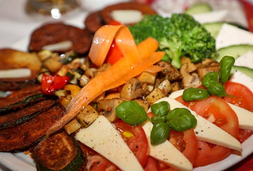 An Italian salad on a plate. Slices of tomato, basil and cheese.