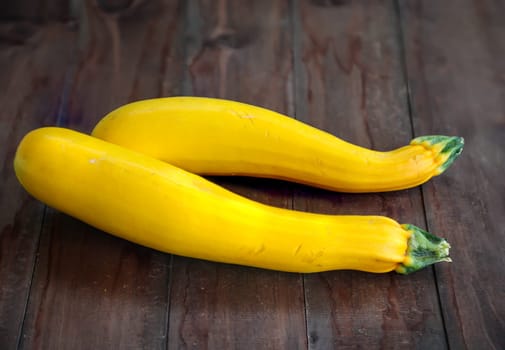 Yellow zucchini on a brown wooden base, ready for preparation.