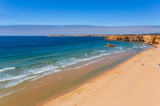Sagres, Portugal - August 25, 2022: View of surfers on sandy beach near Sagres village in Algarve, Portugal
