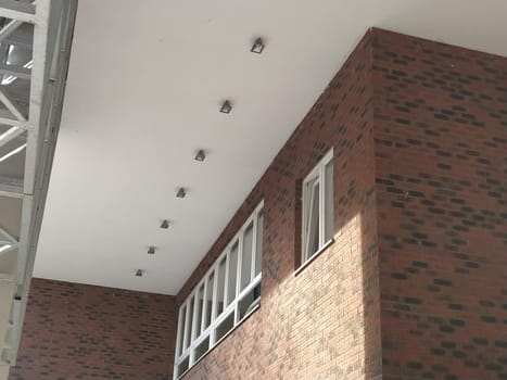 Exterior of the new school. New plastic white windows. Fashionable brown - red facing brick. Metal arch with canopy. Ceiling lighting. School entrance. Serbia, Sremska Mitrovica