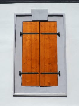 Window with old wooden shutters. Metal curly braces. White wall. Country style. Petrovaradin, Novi Sad, Serbia. Vintage retro architecture building facade