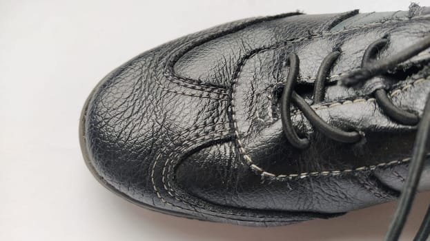 Black leather boots with laces. One shoe on a gray background close-up. Lacquered genuine pigskin. Neat seams.