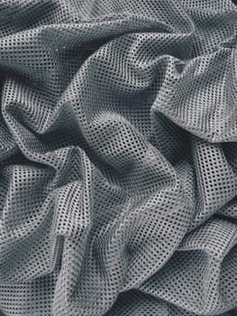 Synthetic fabric with holes laid in waves. Beautiful drape. Fabric for curtains, interior design, and decor. Wrinkled gray fabric