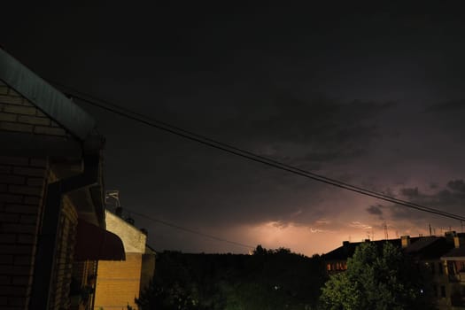Thunderstorm at night over the city. Flashes of lightning and low clouds. Thunder and lightning. Natural element, climate change and weather forecast concept. Discharge of electricity in the sky