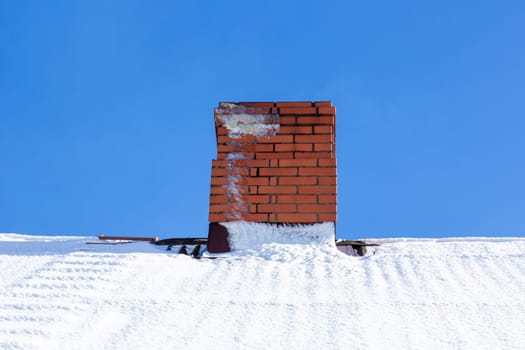 A red brick chimney on a white snowy roof
