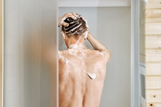 Back view of a man washing hair in the shower