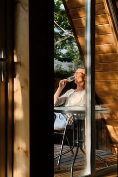 Man sits on terrace in sunny day and drinks cold prosecco