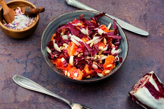 Tasty salad with chicory or radicchio, grapefruit and pine nuts on the table