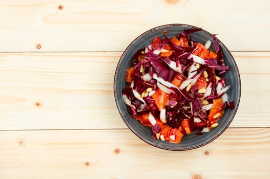 Tasty salad with chicory or radicchio, grapefruit and pine nuts on the table