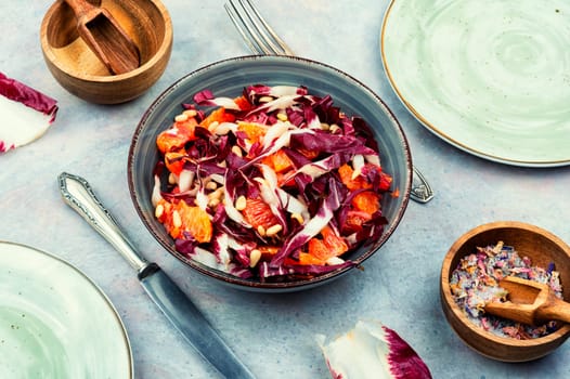 Tasty salad with chicory or radicchio, grapefruit and pine nuts on the table