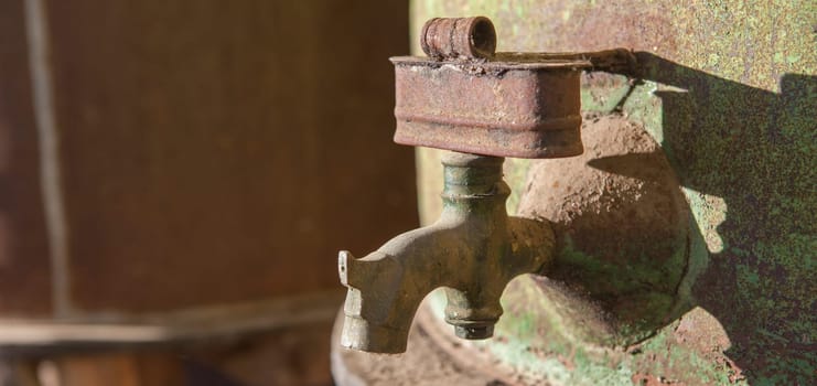 Rusty faucet detail from old olive oil drum. Old farm background