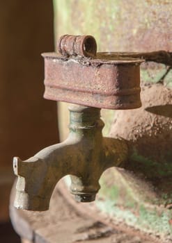 Rusty faucet detail from old olive oil drum. Old farm background