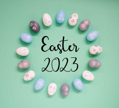 Flat Lay With English Text Easter 2023. Easter Egg Arrangement, Decoration And Ornament. Light Green Paper Background