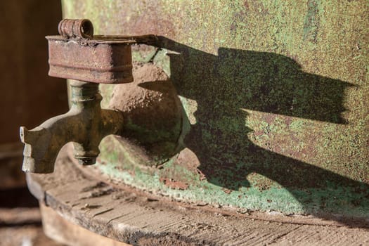 Rusty faucet detail from old olive oil drum. Old farm background