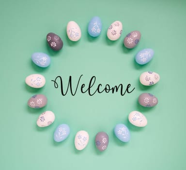 Flat Lay With English Text Welcome. Easter Egg Arrangement, Decoration And Ornament. Light Green Paper Background