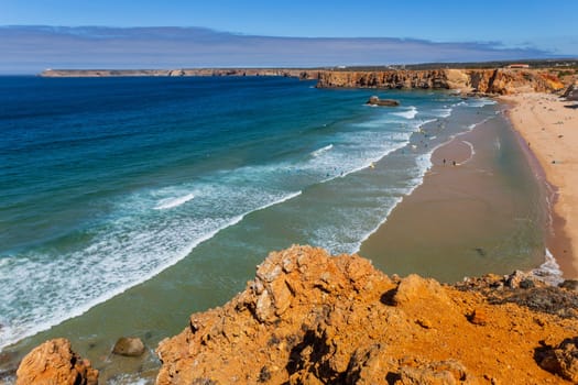Sagres, Portugal - August 25, 2022: View of surfers on sandy beach near Sagres village in Algarve, Portugal