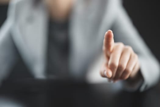 Businesswoman sitting at the black table and pointing by finger. Concept of the leadership and business owner.