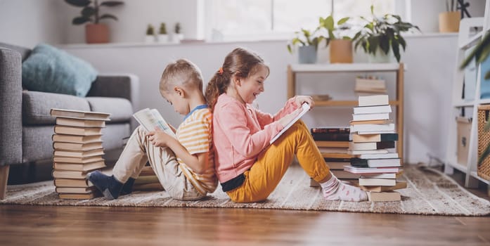 Two children sitting on the floor in the room and reading books. Concept of the family relationship, education and hobby.