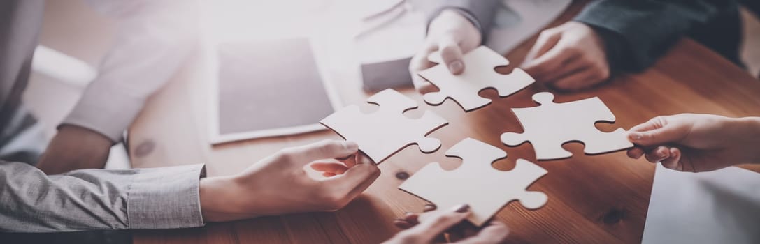 Buisnesswomen and buisnessmen working together while putting together puzzles. Concept of teamwork and cooperation in business