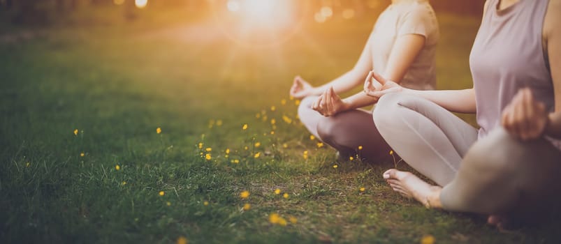 Two women sitting in active wear in lotus position in nature. Concept of healthy lifestyle.