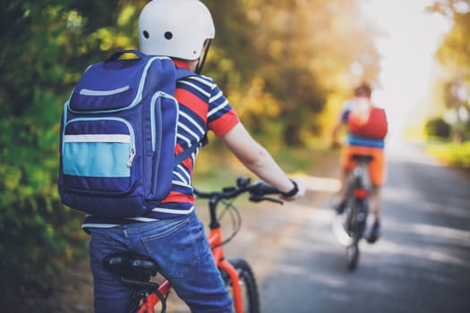 Children riding on bicycles on asphalt road in summer. Concept of hiking, back to school and friendship.