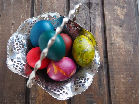 Easter colored eggs in an old metal candy bowl on a wooden table. Easter, the Resurrection of Christ, the Bright Resurrection of Christ, the most ancient and Christian holiday.