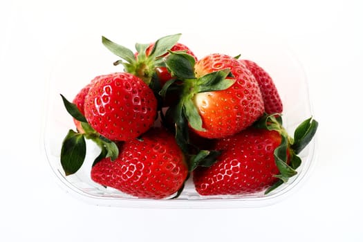 Ripe strawberries in a plastic package on a white background. Delicious fresh berries in a container for sale to customers. Keeping food fresh. Healthy food, vitamins and microelements
