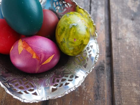 Easter colored eggs in an old metal candy bowl on a wooden table. Easter, the Resurrection of Christ, the Bright Resurrection of Christ, the most ancient and Christian holiday.