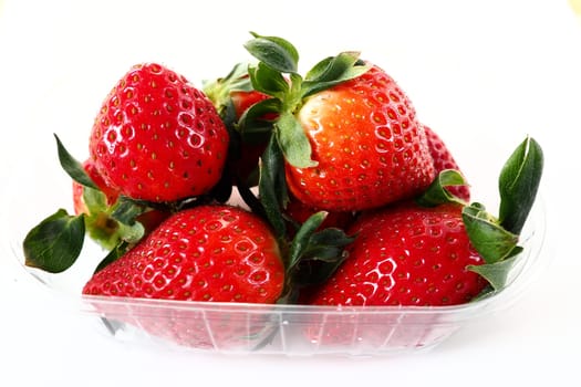 Ripe strawberries in a plastic package on a white background. Delicious fresh berries in a container for sale to customers. Keeping food fresh. Healthy food, vitamins and microelements