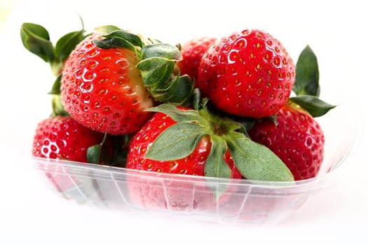 Ripe strawberries in a plastic package on a white background. Delicious fresh berries in a container for sale to customers. Keeping food fresh. Healthy food, vitamins and microelements