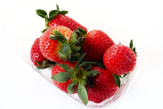 Ripe strawberries in a plastic package on a white background. Delicious fresh berries in a container for sale to customers. Keeping food fresh. Healthy food, vitamins and microelements