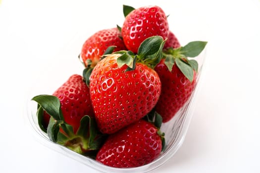 Ripe strawberries in a plastic package on a white background. Delicious fresh berries in a container for sale to customers. Keeping food fresh. Healthy food, vitamins and microelements