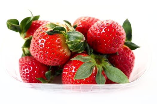 Ripe strawberries in a plastic package on a white background. Delicious fresh berries in a container for sale to customers. Keeping food fresh. Healthy food, vitamins and microelements