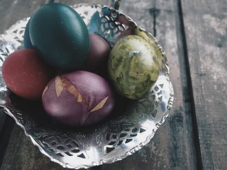 Easter colored eggs in an old metal candy bowl on a wooden table. Easter, the Resurrection of Christ, the Bright Resurrection of Christ, the most ancient and Christian holiday.