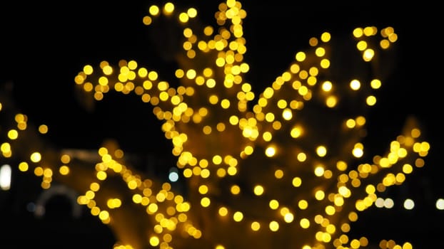 Bokeh on Christmas night. Beautiful round bokeh highlights. Golden and yellow color flashes in the dark. Festive background for New Year Merry Christmas. Blurred defocus. Decoration of city streets