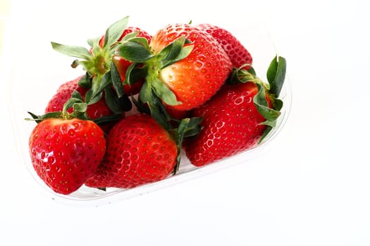 Ripe strawberries in a plastic package on a white background. Delicious fresh berries in a container for sale to customers. Keeping food fresh. Healthy food, vitamins and microelements