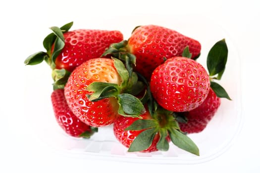 Ripe strawberries in a plastic package on a white background. Delicious fresh berries in a container for sale to customers. Keeping food fresh. Healthy food, vitamins and microelements