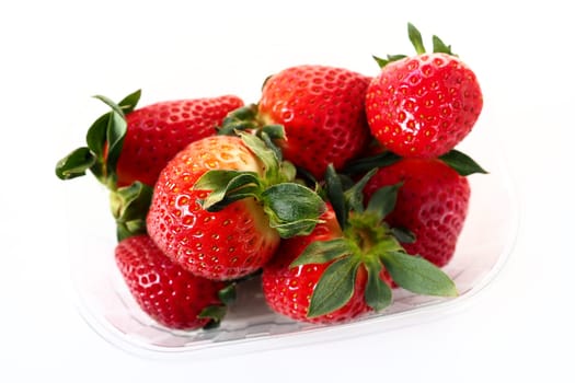 Ripe strawberries in a plastic package on a white background. Delicious fresh berries in a container for sale to customers. Keeping food fresh. Healthy food, vitamins and microelements