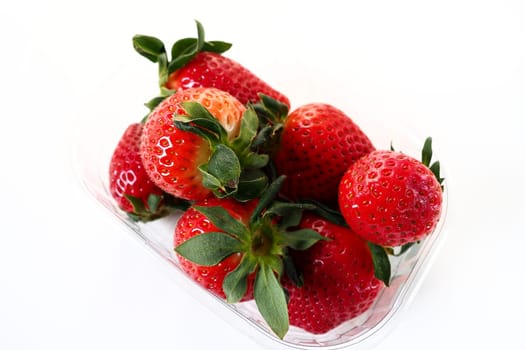Ripe strawberries in a plastic package on a white background. Delicious fresh berries in a container for sale to customers. Keeping food fresh. Healthy food, vitamins and microelements