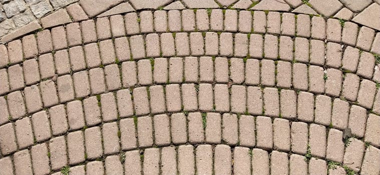 Cobbled street of the old city, lined with square and rectangular stone tiles in a chaotic manner. Soft beige or yellow colors and tones. The texture of the stone. Geometric pattern