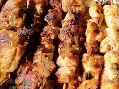 Grilled chicken, pork skewers on sticks. Food from the restaurant. Dish in disposable plastic packaging. Beef patties, chevapy. Food delivery during self-isolation.