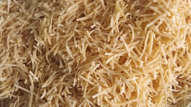 Thin dry vermicelli. Wheat flour product containing gluten, vitamins, carbohydrates, proteins and fats. Small pasta close-up. Fast food