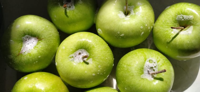 Wet soapy green apples. Thoroughly wash vegetables and fruits with water and soap. Prevention of infectious diseases. Apples close up. Vegetarianism. High glycemic index. Soapy foam sparkles in sunlight.