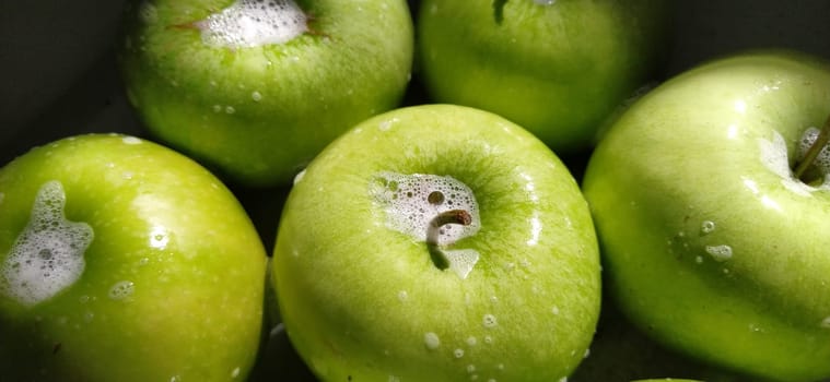 Wet soapy green apples. Thoroughly wash vegetables and fruits with water and soap. Prevention of infectious diseases. Apples close up. Vegetarianism. High glycemic index. Soapy foam sparkles in sunlight.