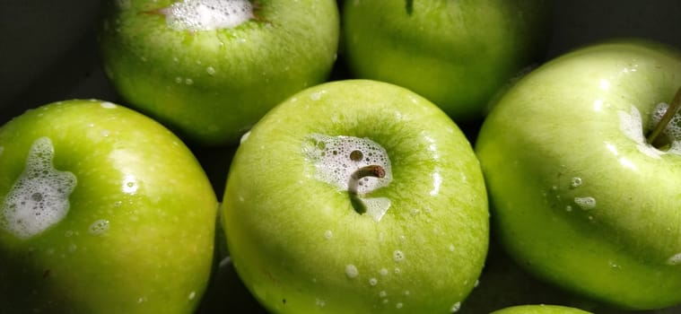 Wet soapy green apples. Thoroughly wash vegetables and fruits with water and soap. Prevention of infectious diseases. Apples close up. Vegetarianism. High glycemic index. Soapy foam sparkles in sunlight.