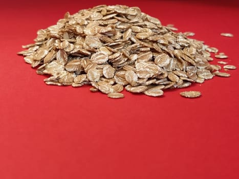 Rye flakes on a red background. Healthy eating and vegetarianism concept