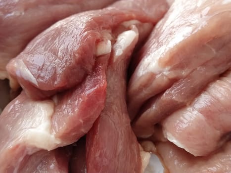 Chunks of meat. Raw pork. Fine veins and texture of the meat. Pink meat with darker red areas. Fresh meat products for sale. Assortment of the grocery store.