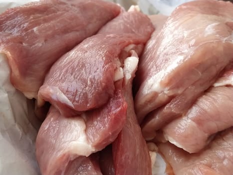 Chunks of meat. Raw pork. Fine veins and texture of the meat. Pink meat with darker red areas. Fresh meat products for sale. Assortment of the grocery store