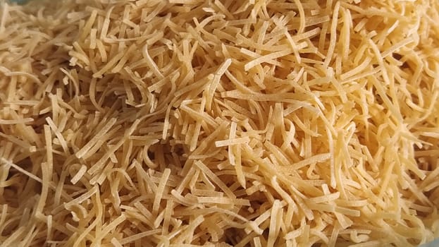 Thin dry vermicelli. Wheat flour product containing gluten, vitamins, carbohydrates, proteins and fats. Small pasta close-up. Fast food